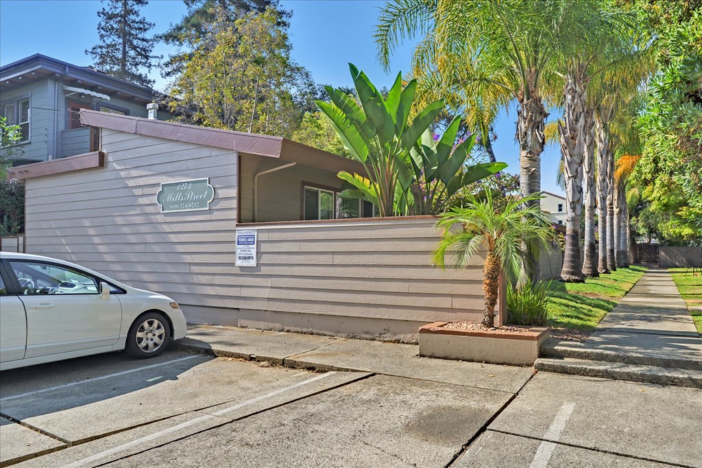a white car parked in front of a house with palm trees