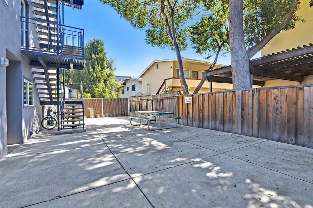 a patio with a fence and a table and a tree