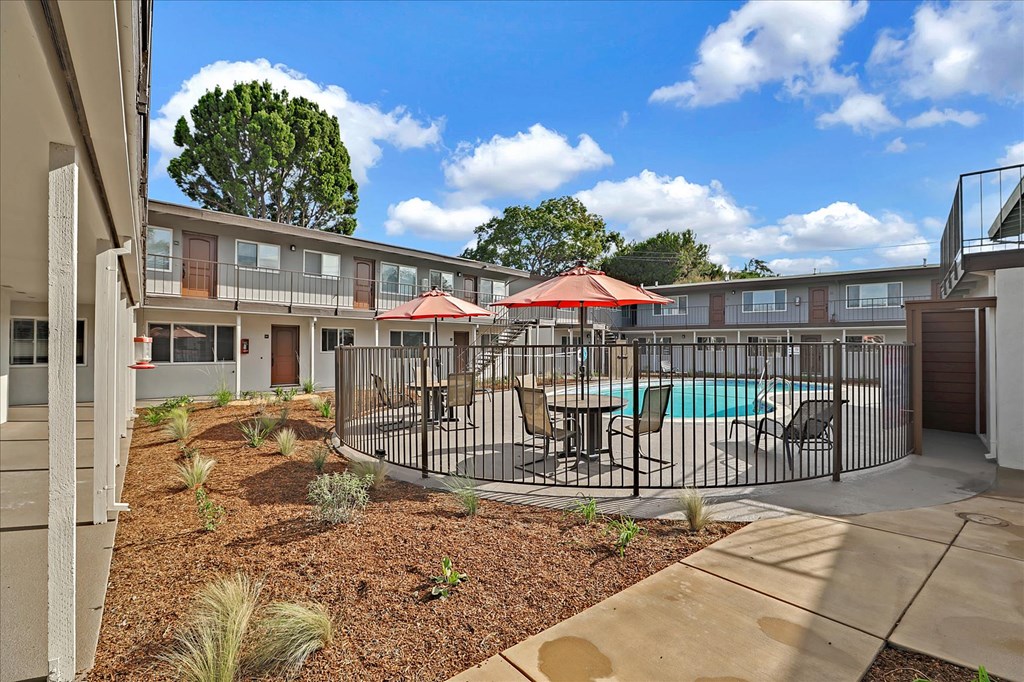 a courtyard with a pool and tables with umbrellas