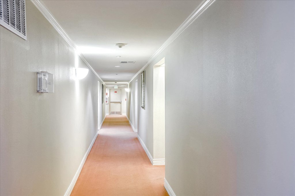 A long hallway with white walls and a brown floor.