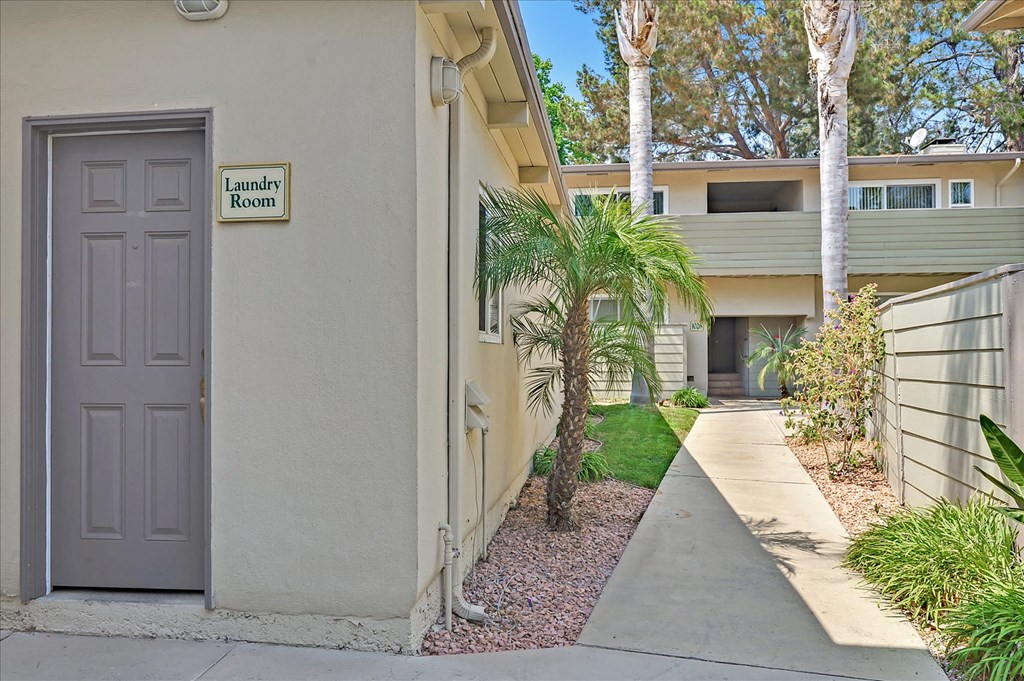 a door on a building with a sidewalk and palm trees