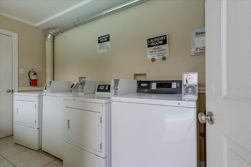 a laundry room with four washers and dryers and a door to a door