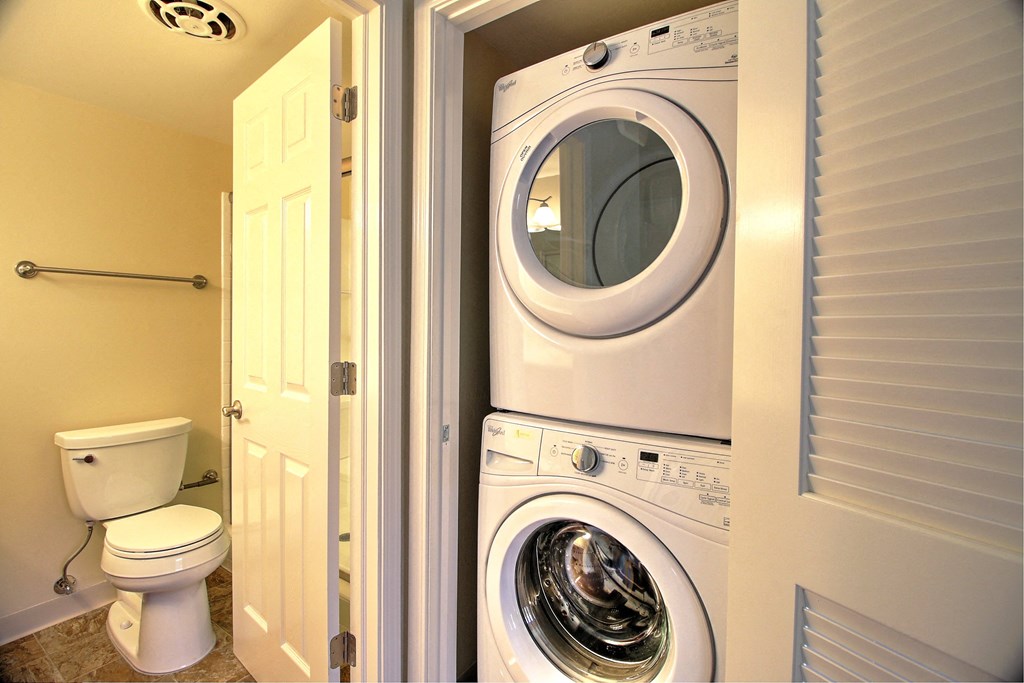 a bathroom with a washing machine and a toilet