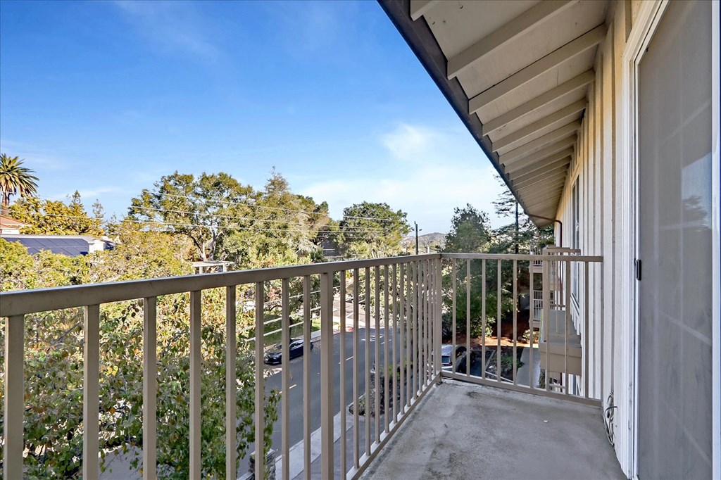 the balcony has a view of the street and trees