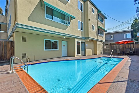 a swimming pool is in front of an apartment building with a pool