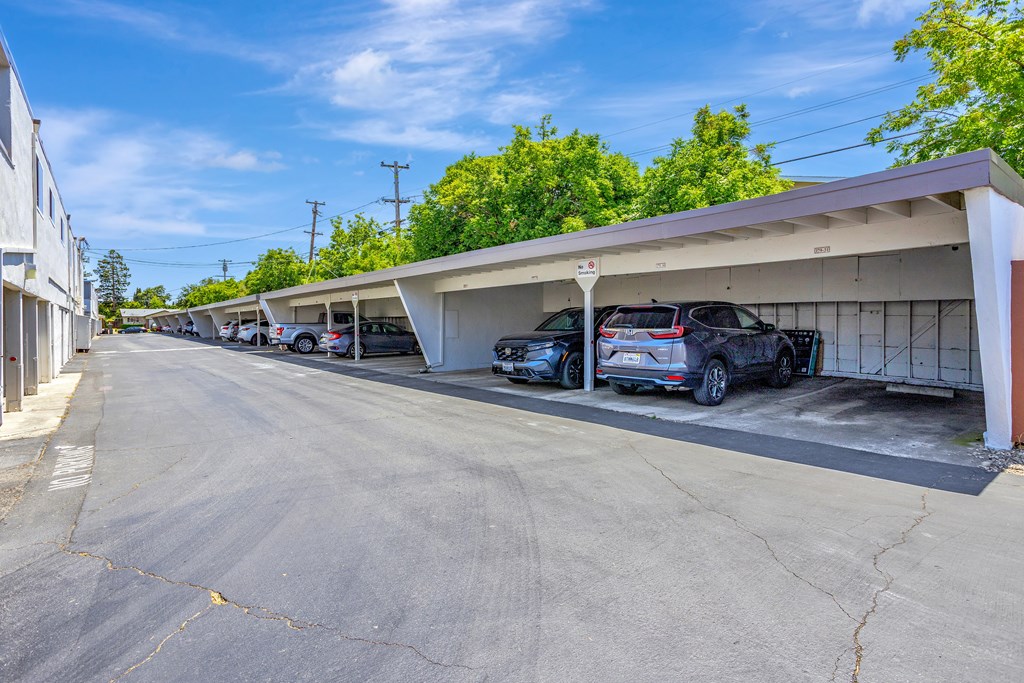 A parking lot with cars parked under a covered area.
