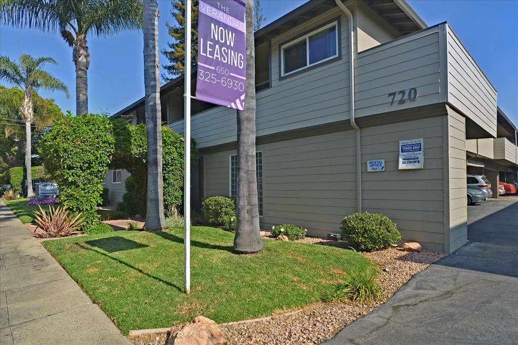 a purple now leasing sign in front of a house
