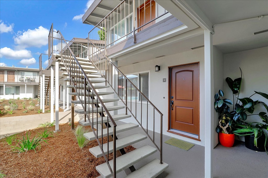 the stairway up to a home with a brown door