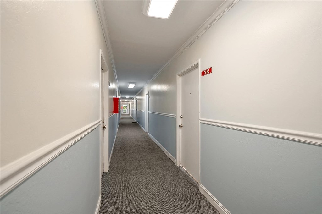 a long hallway with white and blue walls and white doors