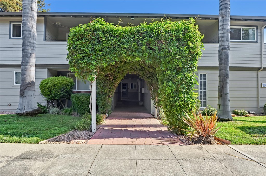 the front of a house with a walkway covered in ivy