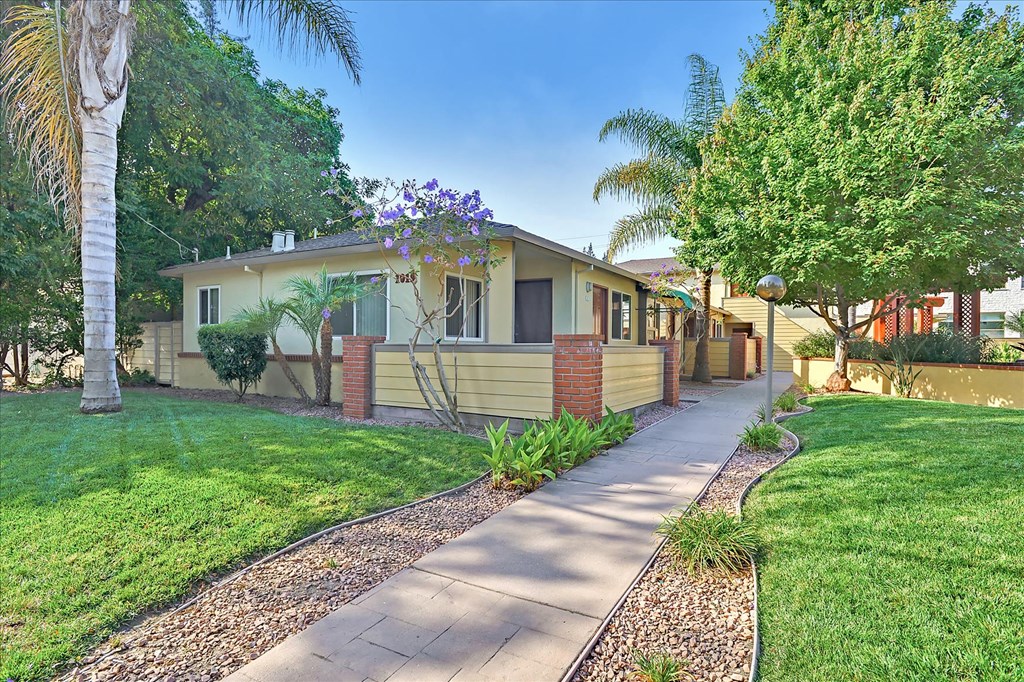 a small yellow house with a sidewalk in front of it