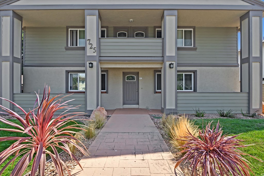 the front of a gray house with a walkway and plants