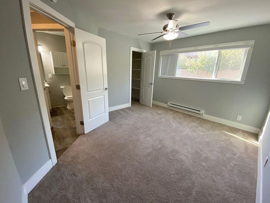 A room with a ceiling fan and a window.