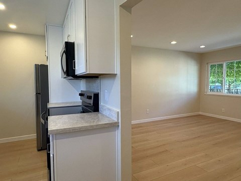A kitchen with white cabinets and a black microwave.