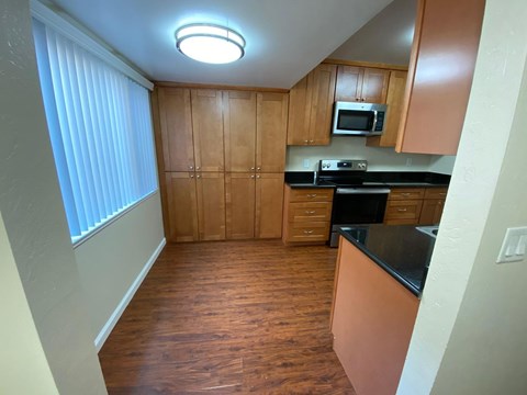 A kitchen with wooden cabinets and black countertops.