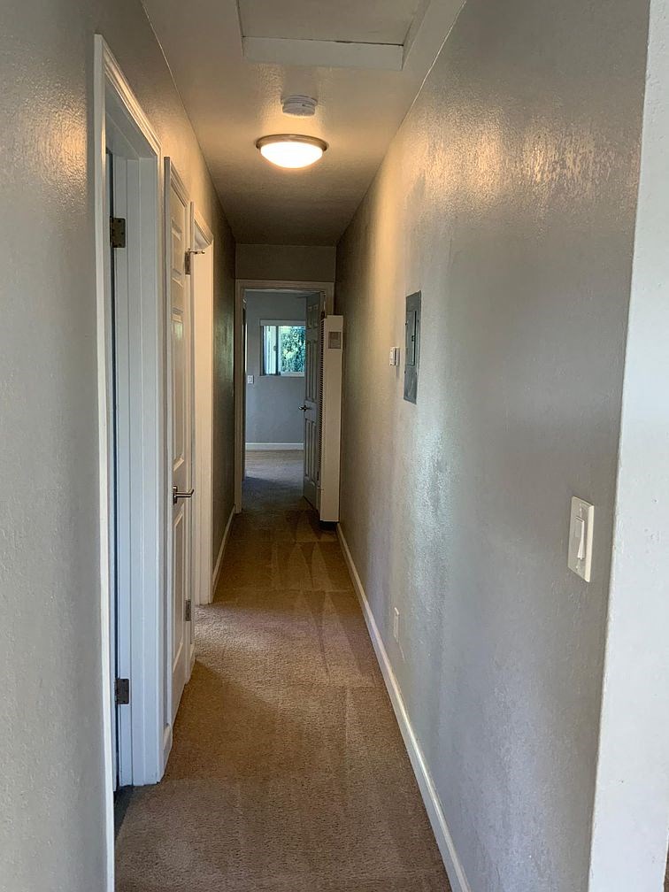 A long, narrow hallway with a carpeted floor and white walls.