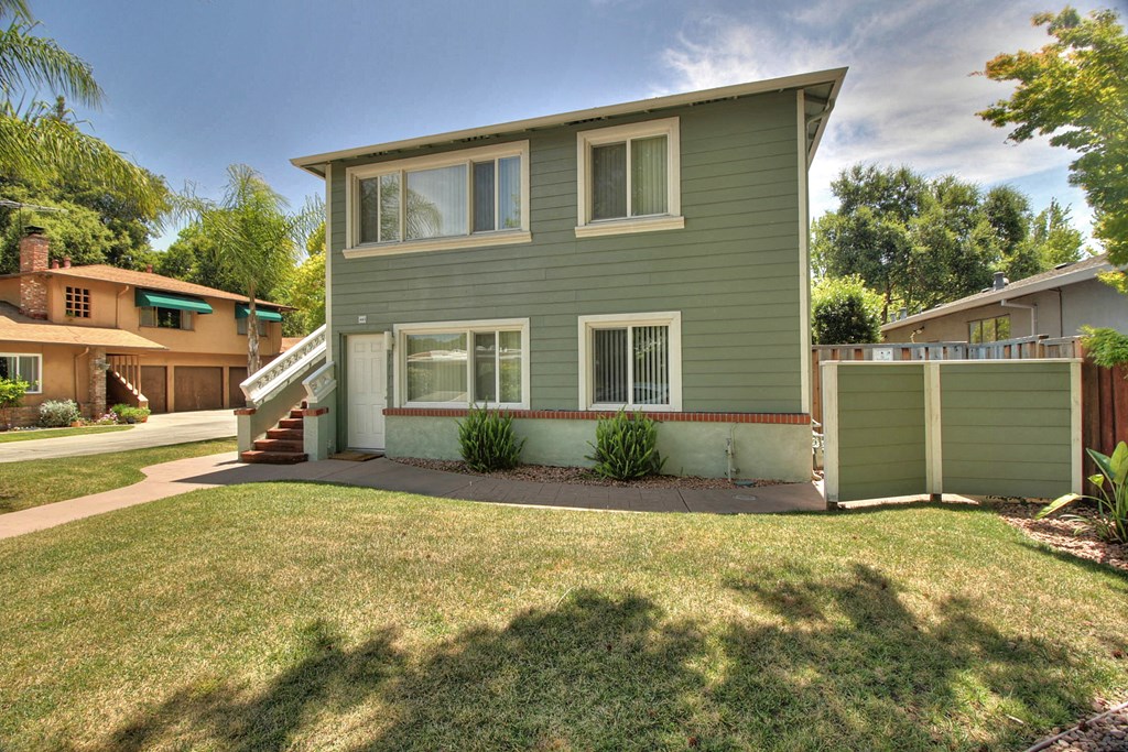 a green house with a yard in front of it