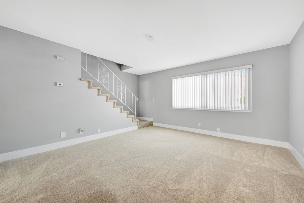 A room with a staircase and a window with blinds.