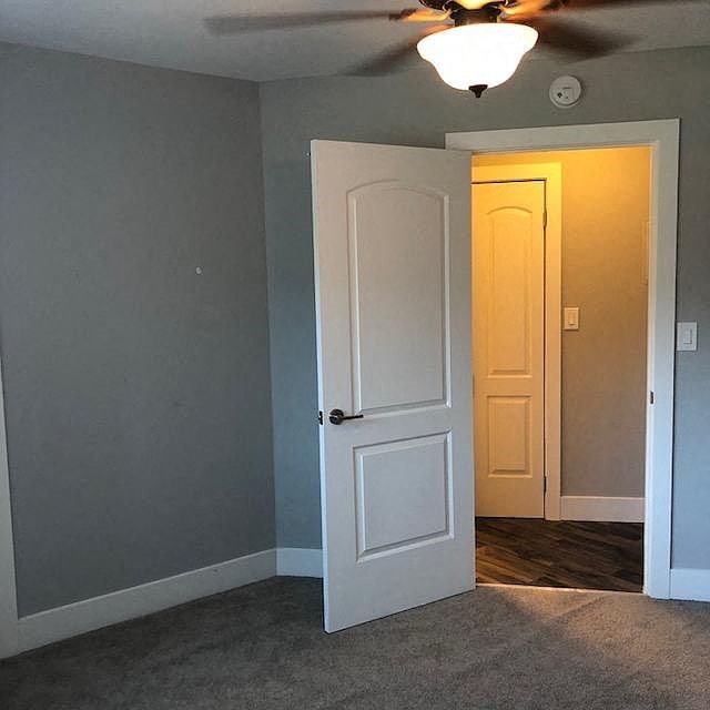 A white door is open to a room with a ceiling fan.
