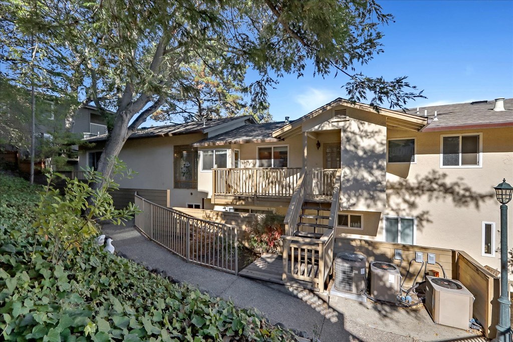 a house with a deck and a tree in front of it