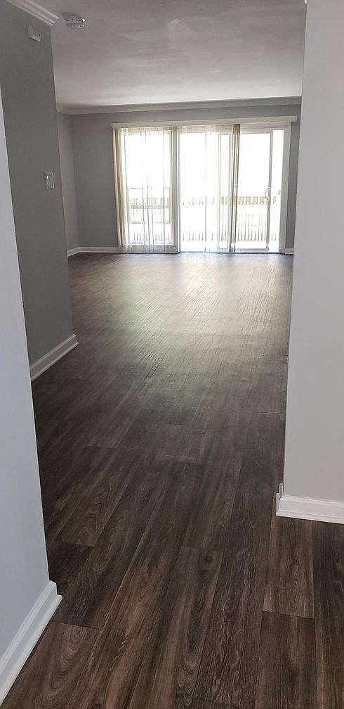 A room with wooden flooring and a doorway leading to another room.