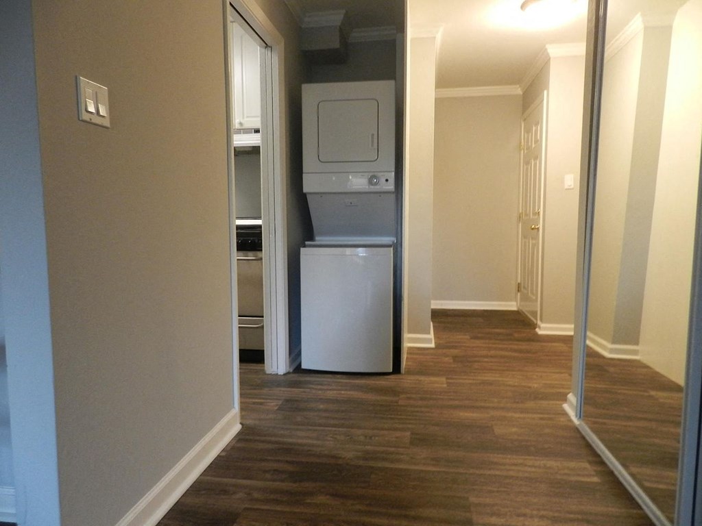 A white fridge in a room with wooden flooring.