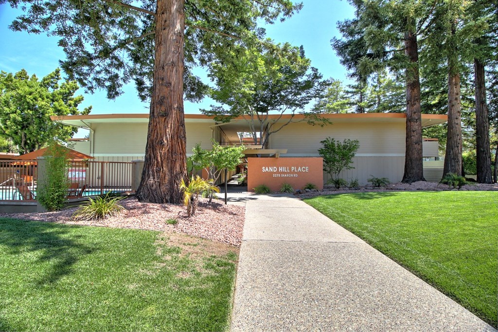 a sidewalk in front of a building with trees