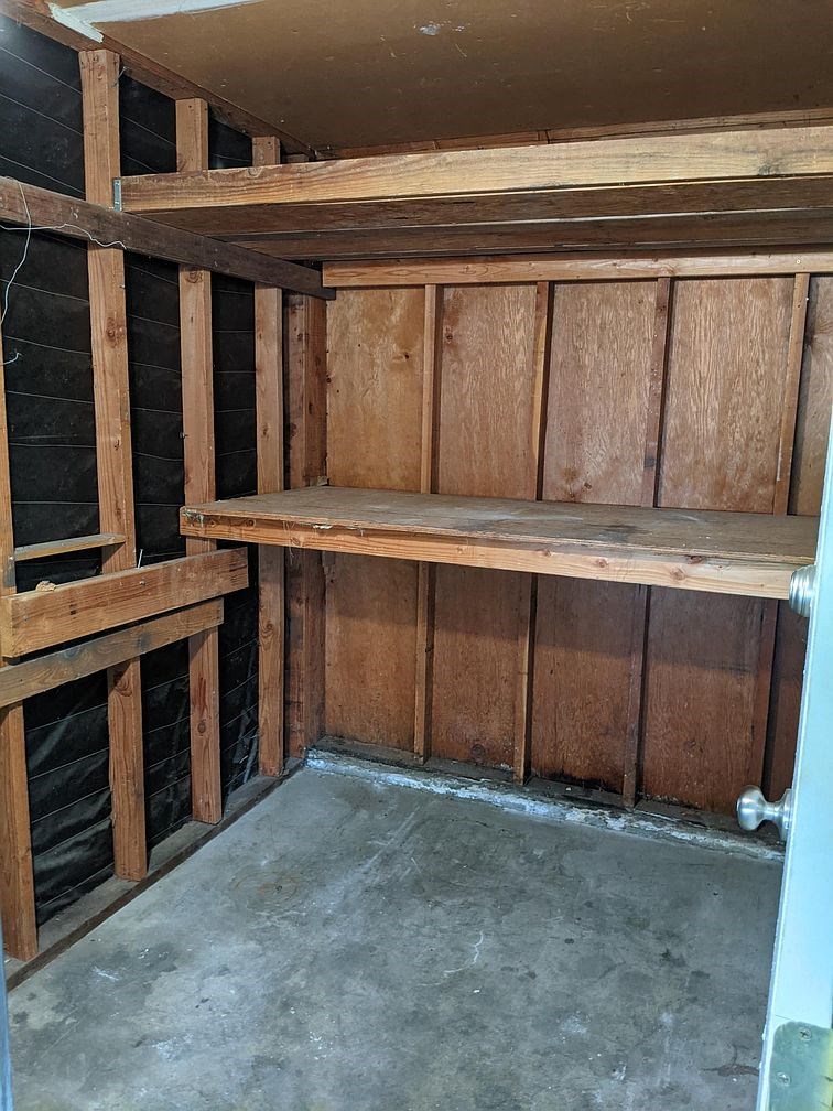 A wooden shelving unit in a room under construction.