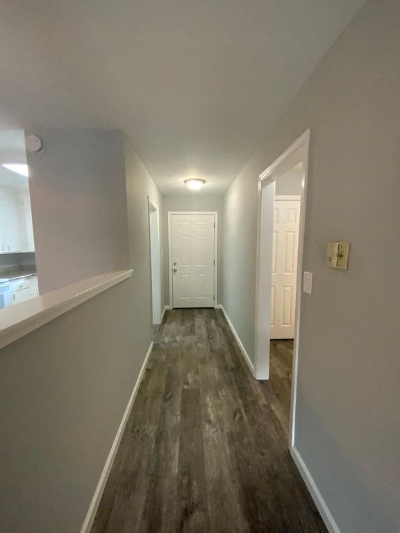 A long hallway with white doors and wood floors.