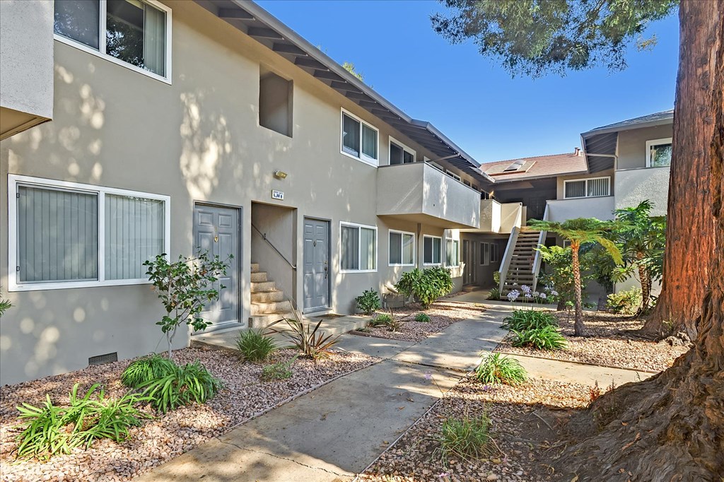a walkway in front of a building with trees and plants