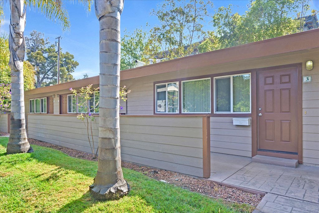 the front of a house with a brown door and grass and trees