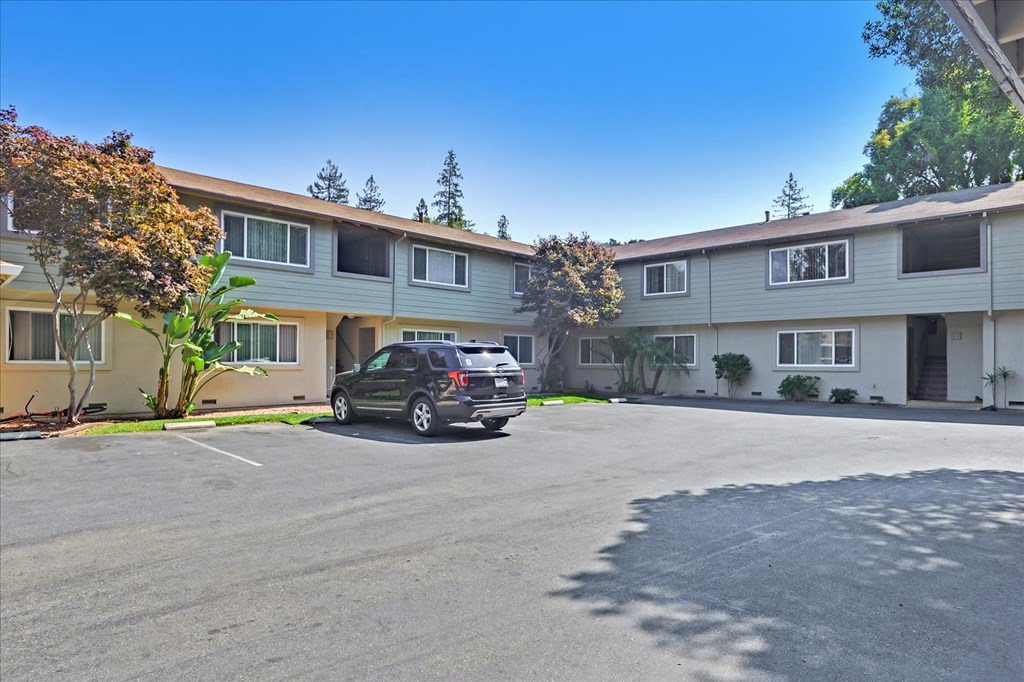 A car is parked in a parking lot in front of a building.
