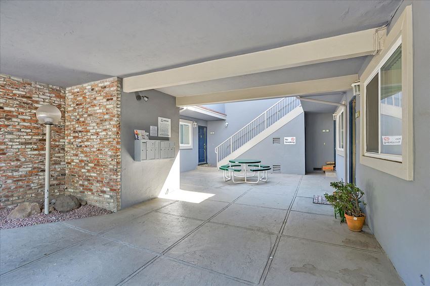 the entrance to a building with a patio with tables and chairs