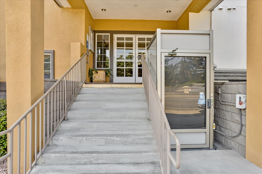 A staircase with a metal railing leads to a glass door.