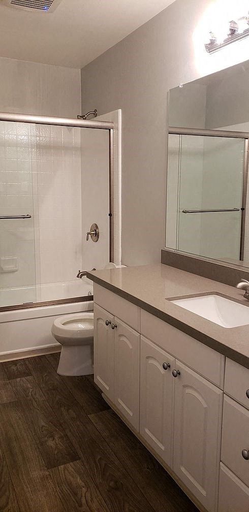 A white bathroom with a toilet, sink, and mirror.