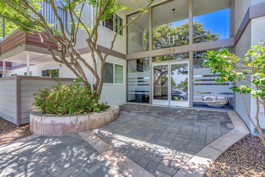 A modern building with a glass entrance and a tree in front.