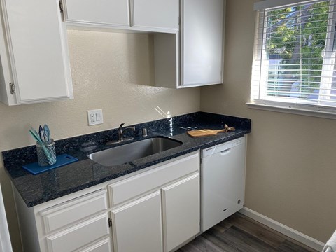 A kitchen with white cabinets and a black countertop.