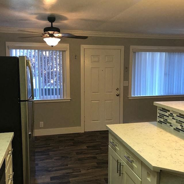 A kitchen with a black fridge and white cabinets.