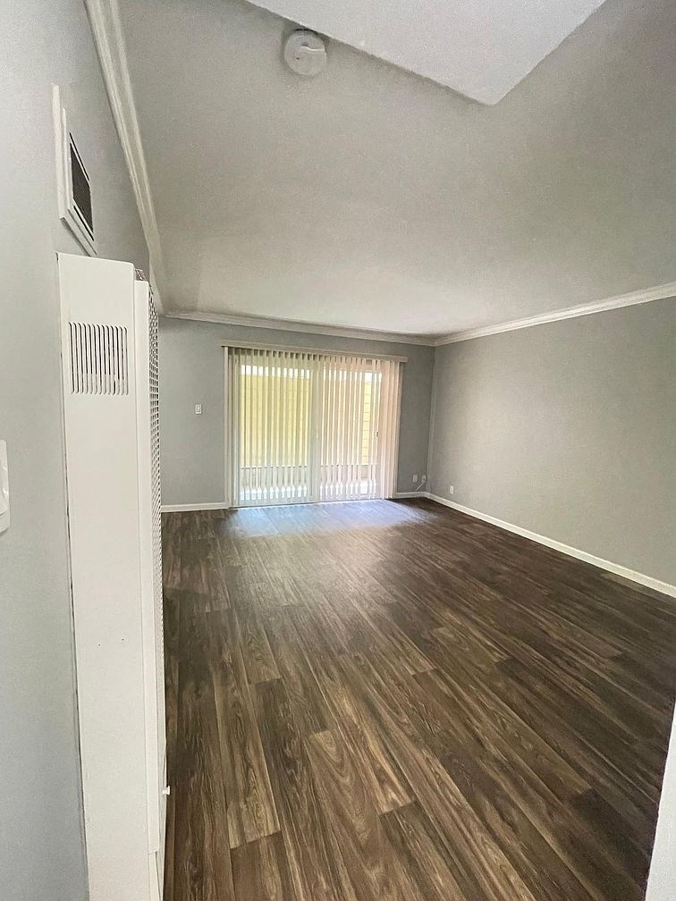 A room with wooden floors and a window with blinds.