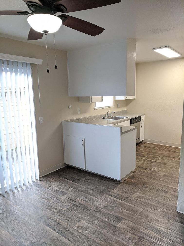 an empty kitchen with a ceiling fan and a window