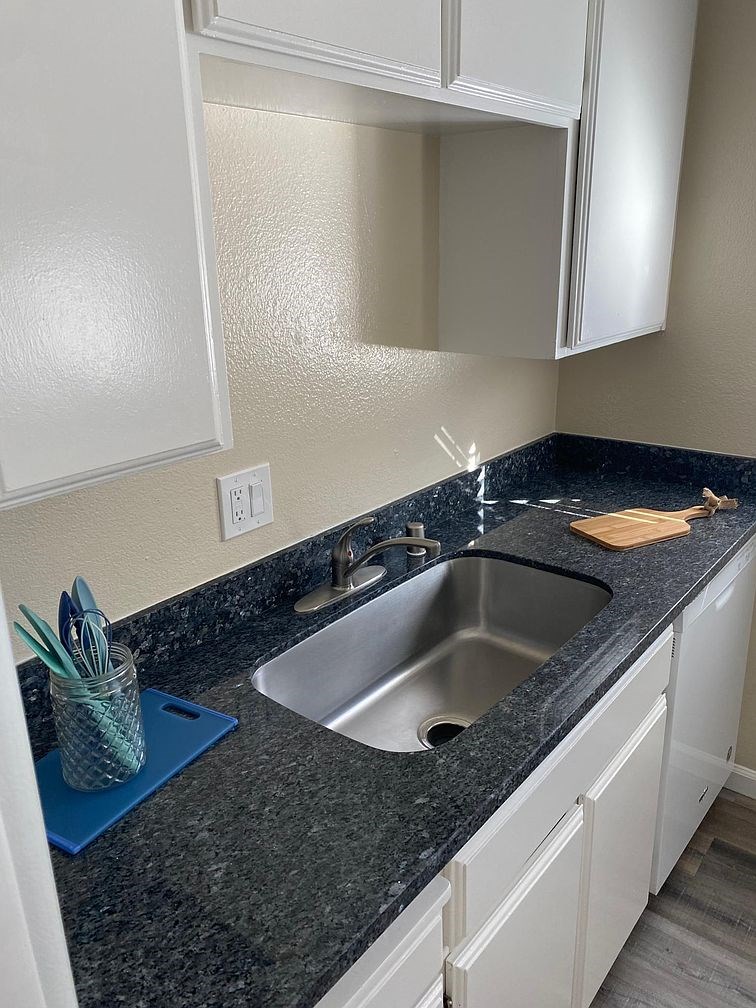 A kitchen with a granite countertop and white cabinets.