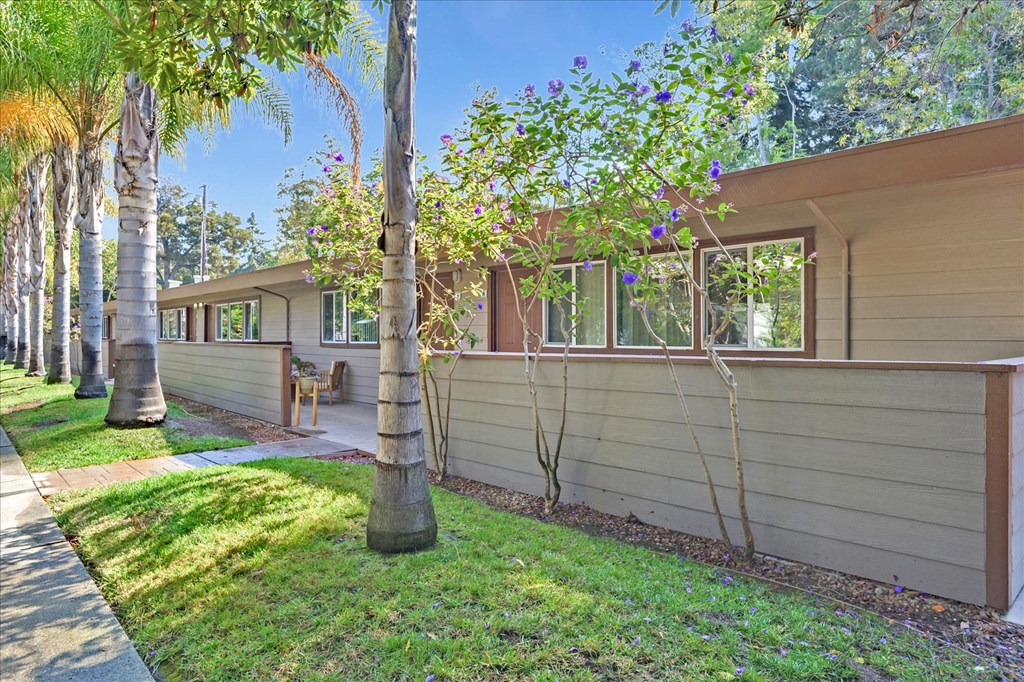 the side of a house with a yard and trees