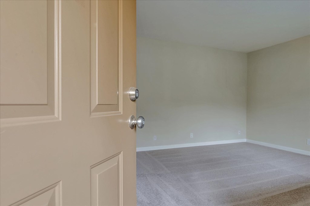 an empty room with a door open to a room with carpet
