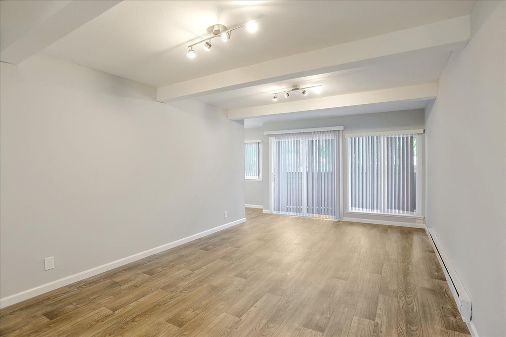 A room with wooden flooring and a window with blinds.