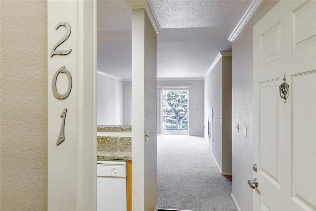 an empty hallway with a door open to a kitchen and a door to a room
