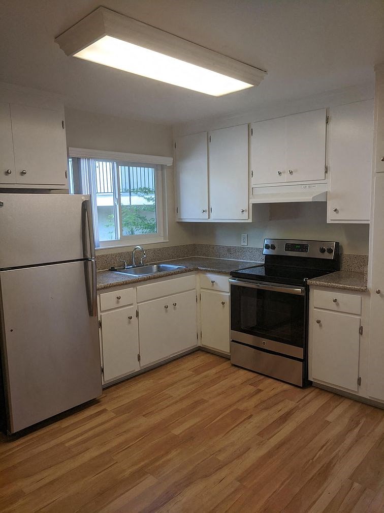 A kitchen with white cabinets and a wooden floor.