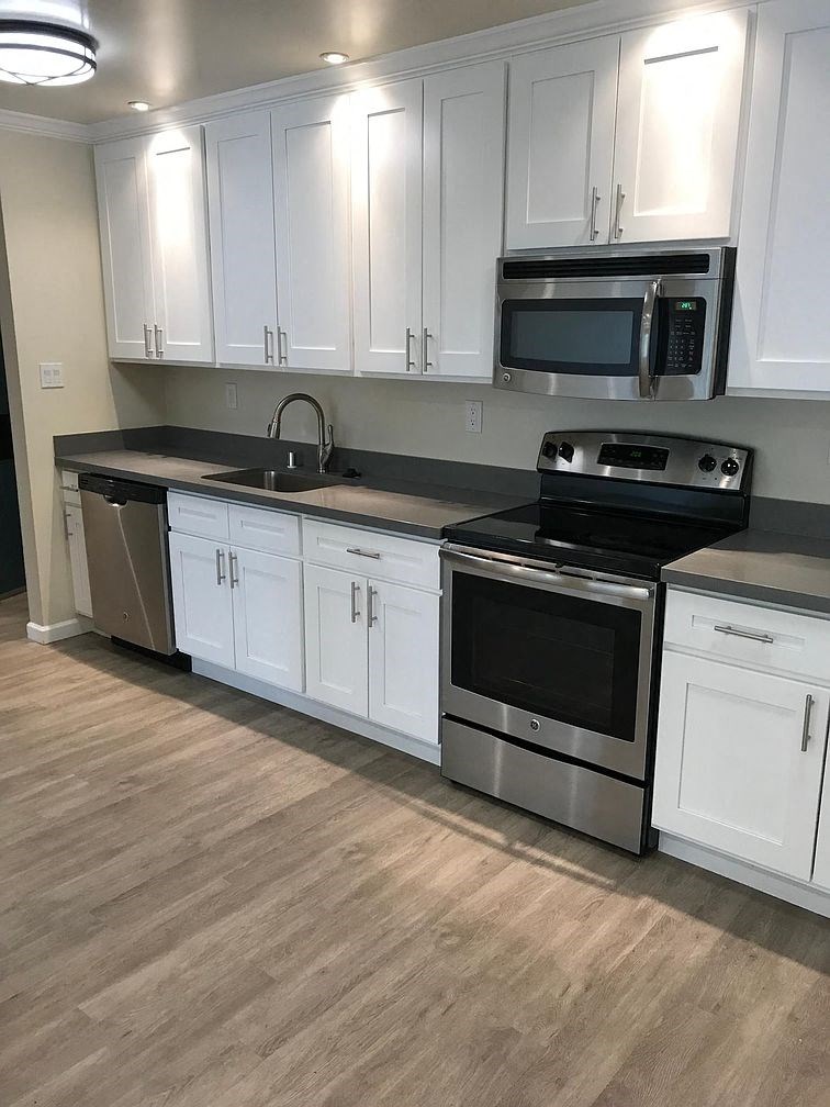 A kitchen with white cabinets and a black countertop.
