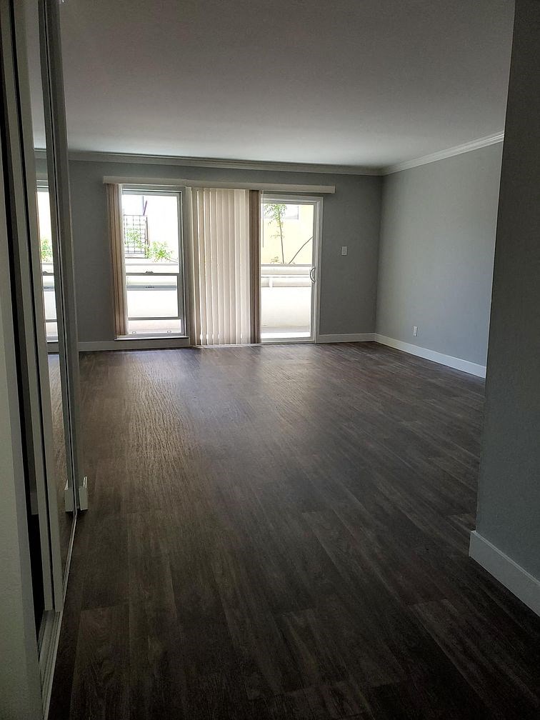 A room with a wooden floor and a sliding glass door.