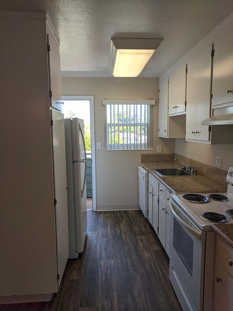A kitchen with a refrigerator, sink, and stove.