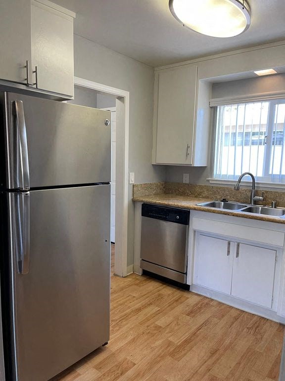 A kitchen with a stainless steel refrigerator and wooden floors.